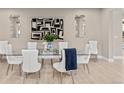 Elegant dining room with a glass-top table, seating for eight, and modern art and light fixtures at 8035 S Kewaunee St, Aurora, CO 80016