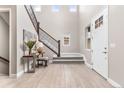 Bright foyer featuring a staircase with iron railings, wood-look floors, and a modern entryway table at 8035 S Kewaunee St, Aurora, CO 80016