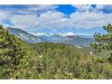 Expansive mountain view from a property surrounded by lush green forests and a blue sky at 1007 Nob Hill Rd, Evergreen, CO 80439