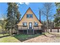 A-frame cabin with a deck is nestled between trees in a scenic outdoor setting at 9185 Jill Dr, Conifer, CO 80433