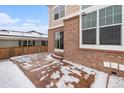 Brick patio area with sliding glass door access to home, and snow on the ground at 24285 E Wagon Trail Ave, Aurora, CO 80016