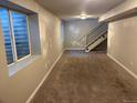 Spacious basement area with carpet flooring, a window well and stairs leading to the upper level at 1222 Yosemite St, Denver, CO 80220