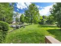 A verdant backyard with manicured lawn and scenic pond featuring mature shade trees at 6305 W 6Th Ave # C12, Lakewood, CO 80214