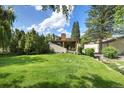 A spacious backyard with green grass, mature trees, and a view of the home's exterior at 6305 W 6Th Ave # C12, Lakewood, CO 80214