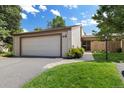 Exterior view of home with a two-car garage, beige siding, and well-maintained landscaping at 6305 W 6Th Ave # C12, Lakewood, CO 80214