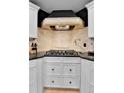 A gourmet kitchen features a cooktop and custom range hood above at 1 Red Fox Ln, Littleton, CO 80127