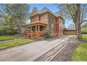 Spacious red brick home with a long driveway leading to a detached garage and a wraparound porch at 835 Niagara St, Denver, CO 80220