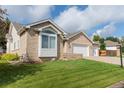 An eye-level, corner view of a brick house with a manicured lawn and a three-car garage at 1809 Little Bear Ct, Longmont, CO 80504