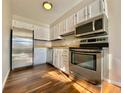 Efficient kitchen with stainless steel appliances, white cabinets, and modern flooring at 1243 Gaylord St # 302, Denver, CO 80206