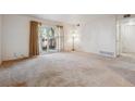 Open living room with neutral carpet, large sliding glass door, and adjacent doorway at 12108 Melody Dr # 103, Denver, CO 80234