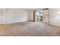 Spacious living room with neutral carpet, large sliding glass door, and adjacent doorway at 12108 Melody Dr # 103, Denver, CO 80234