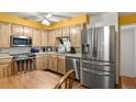 Eat-in kitchen with stainless steel refrigerator, microwave and dishwasher, plus light wood cabinets and countertops at 5030 Titan Ct, Denver, CO 80239