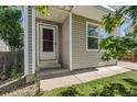 Entrance of the gray home featuring a storm door, white pillars, and a well-maintained lawn at 11898 W Tufts Pl, Morrison, CO 80465