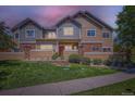 Charming townhouse with a well-maintained lawn, stone accents, and warm exterior lighting at 12856 Jasmine St # E, Thornton, CO 80602