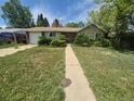 Charming single-story home with well-placed shrubs accenting the exterior and a walkway to the front door at 867 S Grape St, Denver, CO 80246