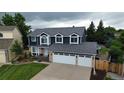 Desirable two-story home boasts a three-car garage, blue siding, and brick accents, complemented by a beautifully landscaped yard at 7404 La Quinta Ln, Lone Tree, CO 80124
