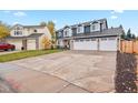 View of home with a three-car garage and long driveway near a yellow house on a sunny day at 7404 La Quinta Ln, Lone Tree, CO 80124