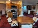 Spacious kitchen with cherry wood cabinets and stainless-steel appliances adjacent to dining area at 6958 Brentwood Ct, Arvada, CO 80004