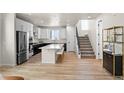 Open kitchen featuring an island, stainless steel appliances, and adjacent staircase at 12374 Farmview St, Thornton, CO 80241