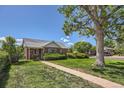 Inviting brick home featuring a well-manicured lawn and mature trees, offering great curb appeal at 2361 Olive St, Denver, CO 80207