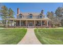 Stunning home showcasing lush greenery, a brick facade, and an inviting covered front porch at 38666 County Road 21, Elizabeth, CO 80107