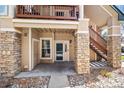 Inviting condo entrance with stone pillars, convenient stairs, and a private covered patio at 4084 S Crystal Cir # 104, Aurora, CO 80014