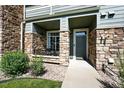 Inviting condo entrance with stone accents, showcasing a well-maintained exterior and a private front porch at 474 Black Feather Loop # 406, Castle Rock, CO 80104