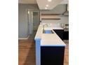 Modern kitchen featuring an island with sink, stainless steel appliances, and wood shelves at 1040 Stuart St, Denver, CO 80204