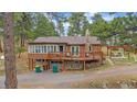 Log-sided home with an attached garage, stone foundation, expansive deck, and outdoor pergola at 24699 Us Hwy 40, Golden, CO 80401