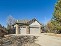 Lovely home featuring a three-car garage, stone accents, and a spacious driveway surrounded by mature trees on a sunny day at 2227 Chestnut Cir, Erie, CO 80516