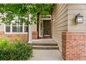 Close-up of the front door entry with brick accents and well manicured garden at 13486 Clayton St, Thornton, CO 80241