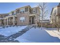 Two-story brick home with gray accents, snowy front yard, and a walkway leading to the front door at 16630 E Virginia Ave, Aurora, CO 80017