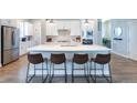 Modern kitchen features a large island with seating, stainless steel appliances, and sleek white cabinetry at 21574 E 59Th Dr, Aurora, CO 80019
