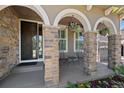 Inviting front porch with stone columns, comfortable seating, and decorative hanging flower baskets at 12015 Blackwell Way, Parker, CO 80138