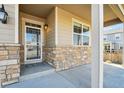 Inviting front porch with stone accents, classic lantern, and a secure screen door at 806 Peony Ct, Brighton, CO 80601