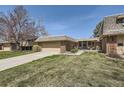 Charming brick home showcasing a well-manicured lawn and attached two-car garage at 32 Eagle Dr, Littleton, CO 80123