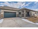 Tan and green two-car garage home with stone accents and covered entry at 804 W 128Th Pl, Westminster, CO 80234