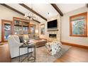 Cozy living room featuring wood floors, beamed ceilings, a stone fireplace, and oversized windows at 6928 S Eaton St, Littleton, CO 80128