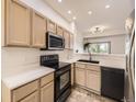 Well-lit kitchen featuring sleek, black appliances and view to the living room at 12265 E 2Nd Dr, Aurora, CO 80011