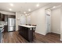 Bright kitchen with dark cabinets, stainless steel appliances, quartz countertops, and a spacious center island at 155 S Monaco Pkwy # 114, Denver, CO 80224