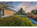 Well-maintained lawn of brick home with mature trees and snow remnants at 3810 Urban St, Wheat Ridge, CO 80033