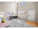 A bright living room with high ceilings, large windows, and carpeted floors offers a welcoming entrance at 13445 Kearney St, Thornton, CO 80602