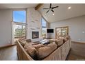 Cozy living room with stone fireplace, hardwood floors, and a large sectional sofa at 7082 Silverhorn Dr, Evergreen, CO 80439
