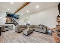 Open living room with neutral-toned furniture, wood-look flooring, and rustic beam at 14867 E Pacific Pl, Aurora, CO 80014