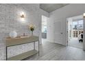 Stylish condo entryway with a textured brick wall, light wood floors, and modern furnishings at 1700 Bassett St # 1301, Denver, CO 80202