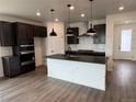 Modern kitchen with dark cabinets, stainless steel appliances, and a large island with pendant lighting at 2141 S Irvington St, Aurora, CO 80018