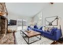 Open-concept living room featuring hardwood floors, a stone fireplace, and a large window at 27732 Squaw Pass Rd, Evergreen, CO 80439