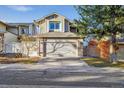 Two-story home showcasing a two-car garage, driveway, mature trees, and well-maintained landscaping at 2067 E Phillips Pl, Centennial, CO 80122