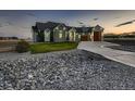 View of the house with a lush green lawn, rocks, and concrete driveway leading to modern garage doors at 29780 E 162Nd Ave, Brighton, CO 80603