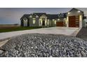 Gorgeous exterior of a gray house featuring a concrete driveway, stone landscaping, and modern garage doors at 29780 E 162Nd Ave, Brighton, CO 80603